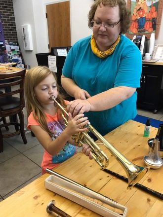 woman showing girl how to use trumpet