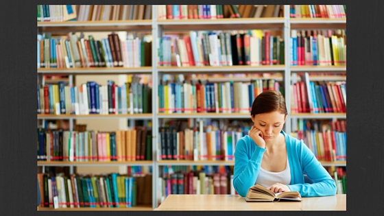 person reading in front of book shelf