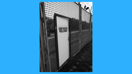 Fence with door that says Refugees Welcome